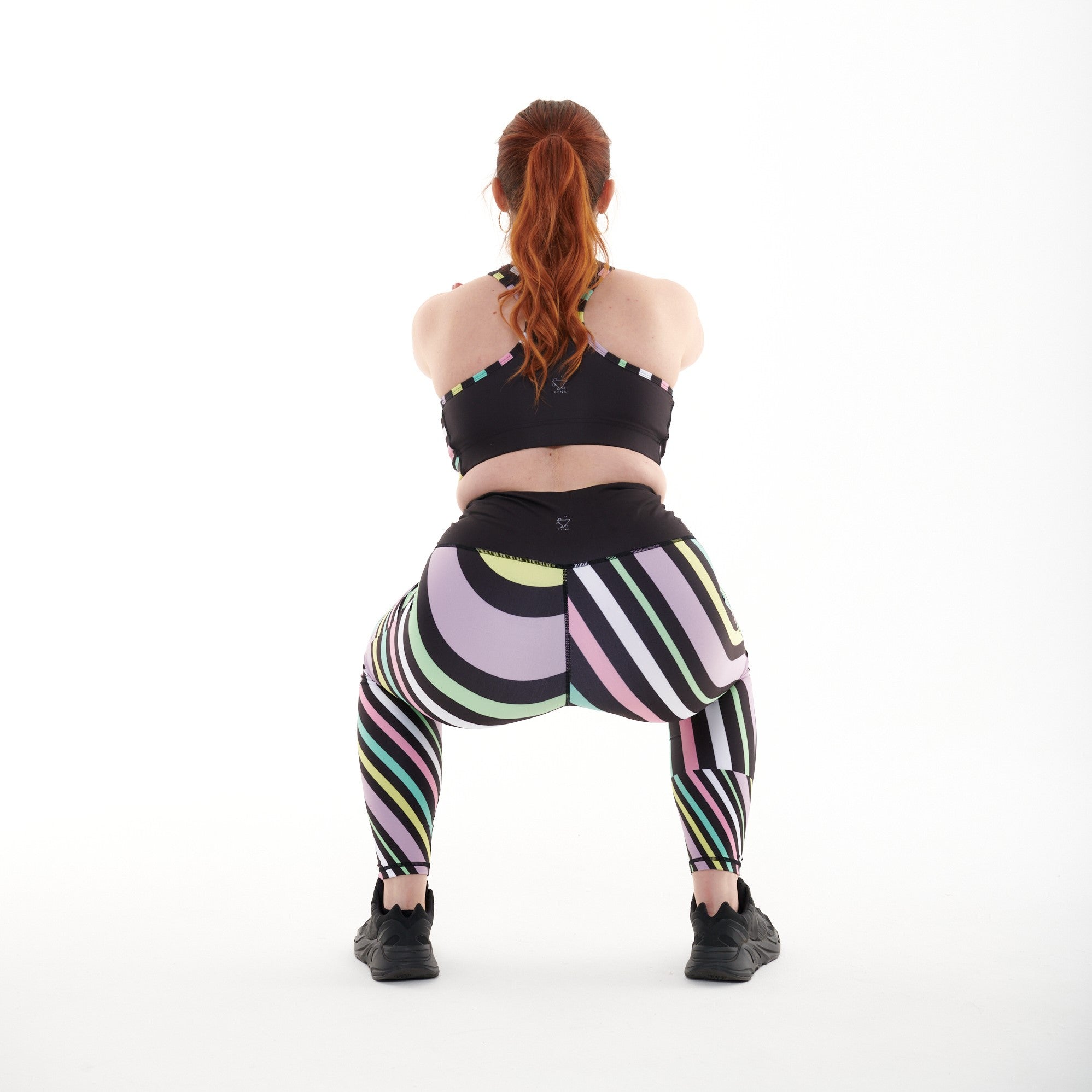 White Oliver Aso-Oke Pastel Vibrant activewear leggings shown during squat exercise, featuring colorful, traditional-inspired patterns.
