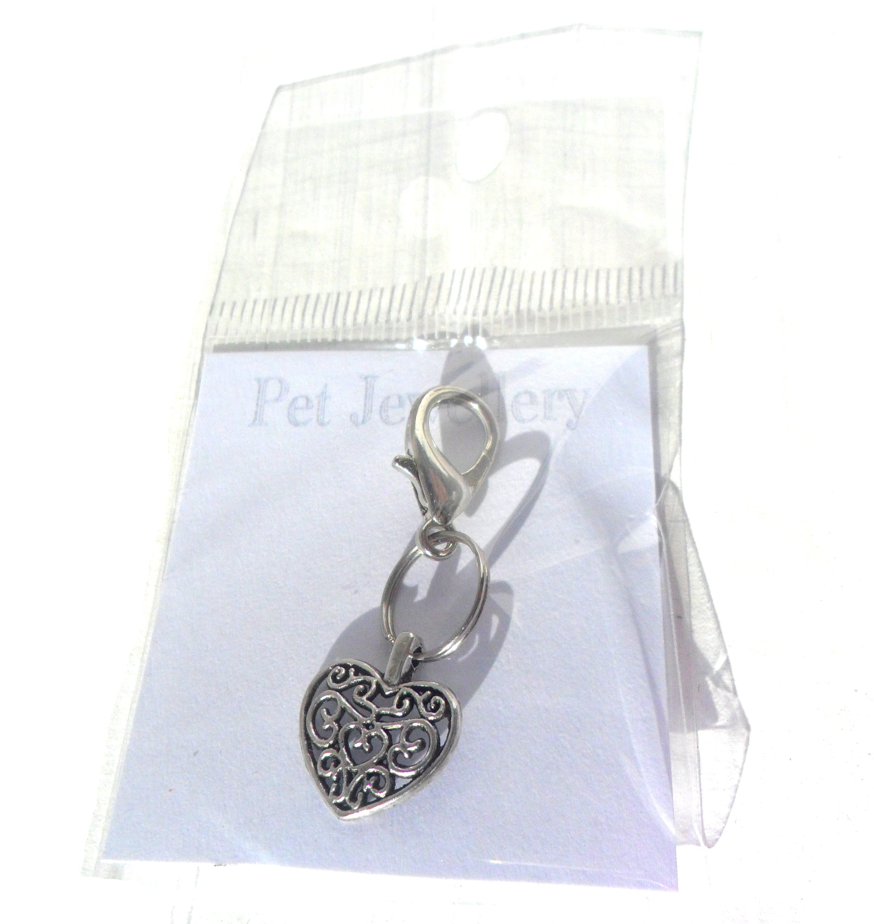 Salmon Oscar filigree heart pet charm attached to a leash or collar, decorative silver accessory for pet wear.
