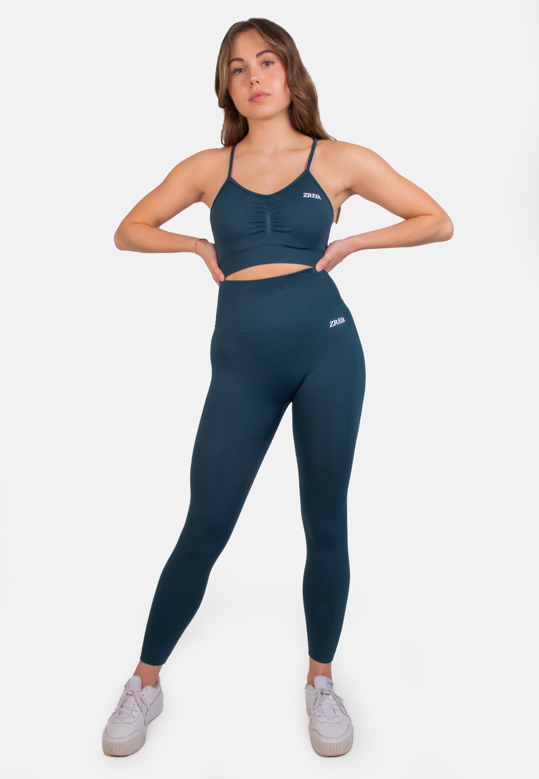 Dark teal seamless sports bra from Pear Juniper, styled with matching leggings for activewear or casual outfit.