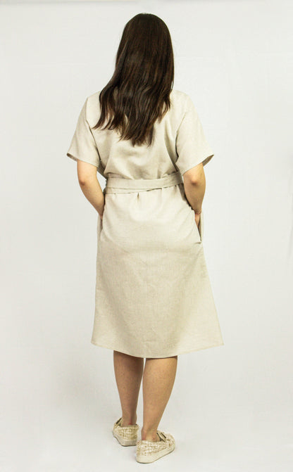 Pale pink linen wrap dress from Magenta Sugarplum featuring a fitted waist and flowing skirt, perfect for warm weather.