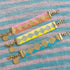 Yellow Athena Soleil bracelets featuring colorful beaded designs on a display, showcasing vibrant, stylish jewelry accessories.