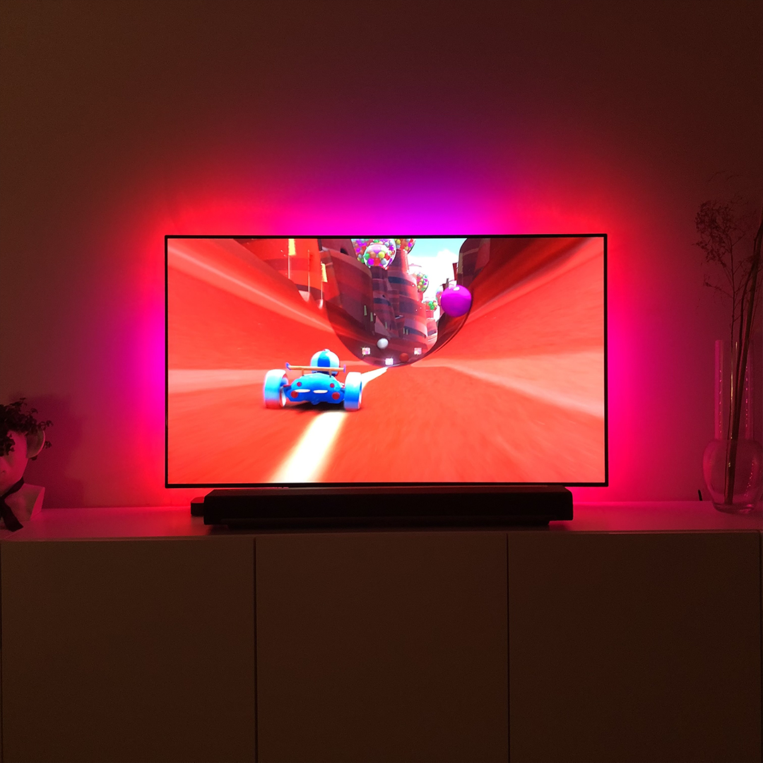 Pink Trillium LED TV mood light illuminating a modern living room with colorful ambient lighting.