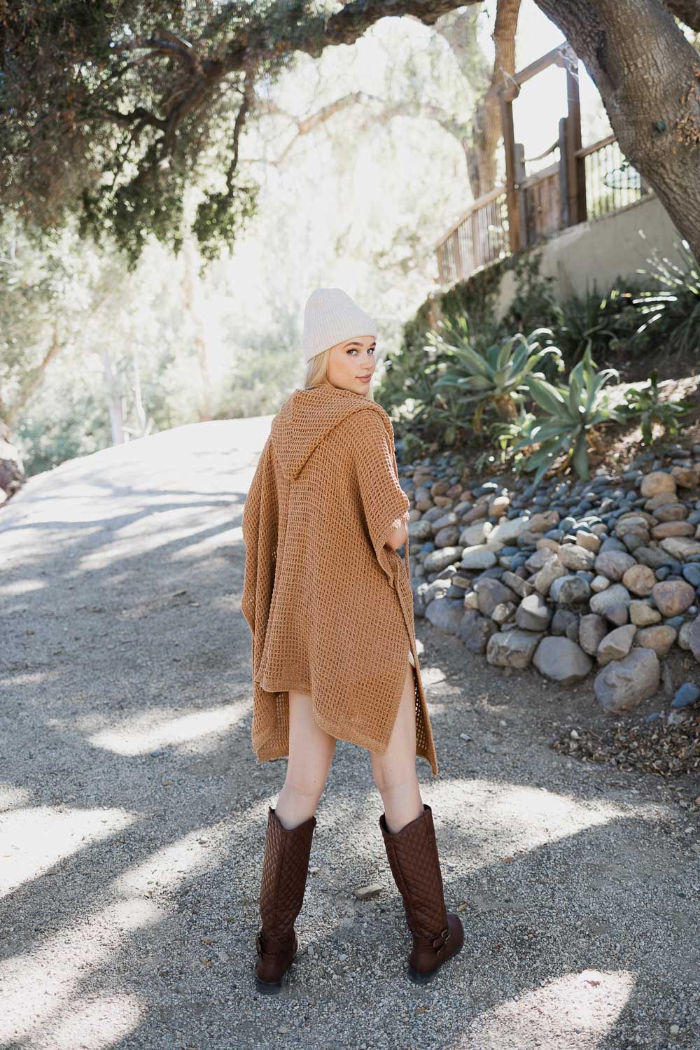 Camel-colored cozy soft waffle hooded ruana from Periwinkle Aether, draped over a chair, showcasing its textured fabric and relaxed style.