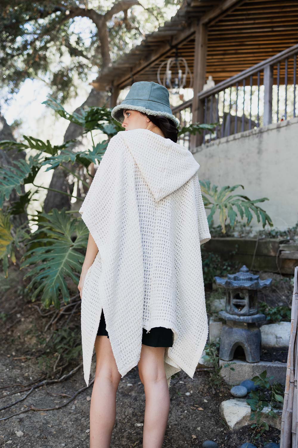 Ivory cozy soft waffle hooded ruana by Periwinkle Aether, showcasing its textured fabric and relaxed fit, perfect for layering.