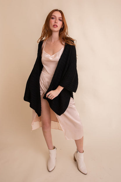 Black ridged rib knit ruana by Periwinkle Aether, stylish layering wrap with textured fabric and open front design.