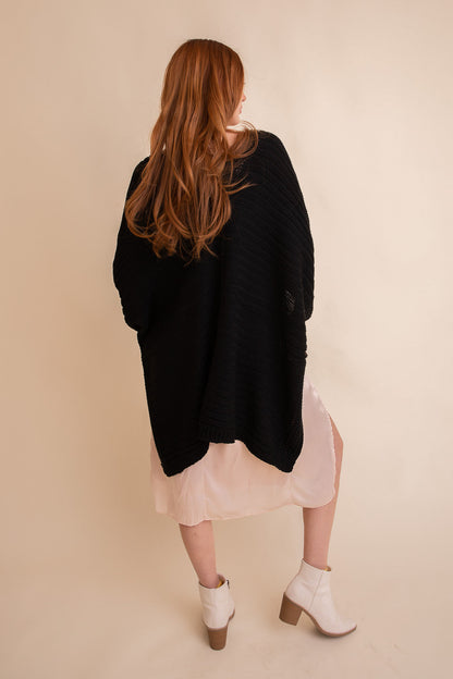 Black ridged rib knit ruana by Periwinkle Aether, stylish layered wrap with textured ribbed design, perfect for cozy layering.