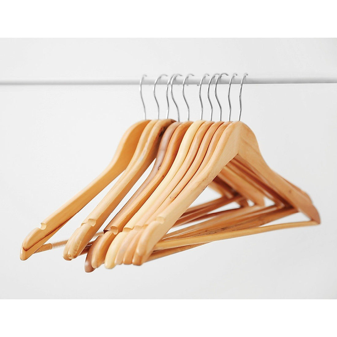 Set of 120 wooden clothes hangers by Magenta Danae, displaying coat, pant, and suit hangers on a wardrobe rack.