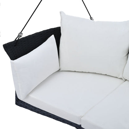 Black wicker hanging porch swing for 2 from Carmine Juneberry, designed for garden relaxation, with rattan and white cushions.