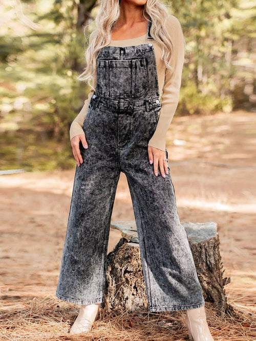 Vintage washed wide leg denim overalls for women with front pockets by Ruby Styx, shown hanging on a wooden background.