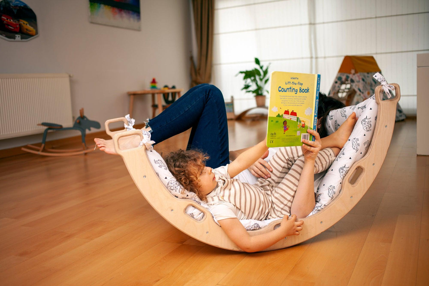 Red Oceanus climbing arch with origami-patterned pillow, modern furniture piece featuring a curved design and decorative pillow.