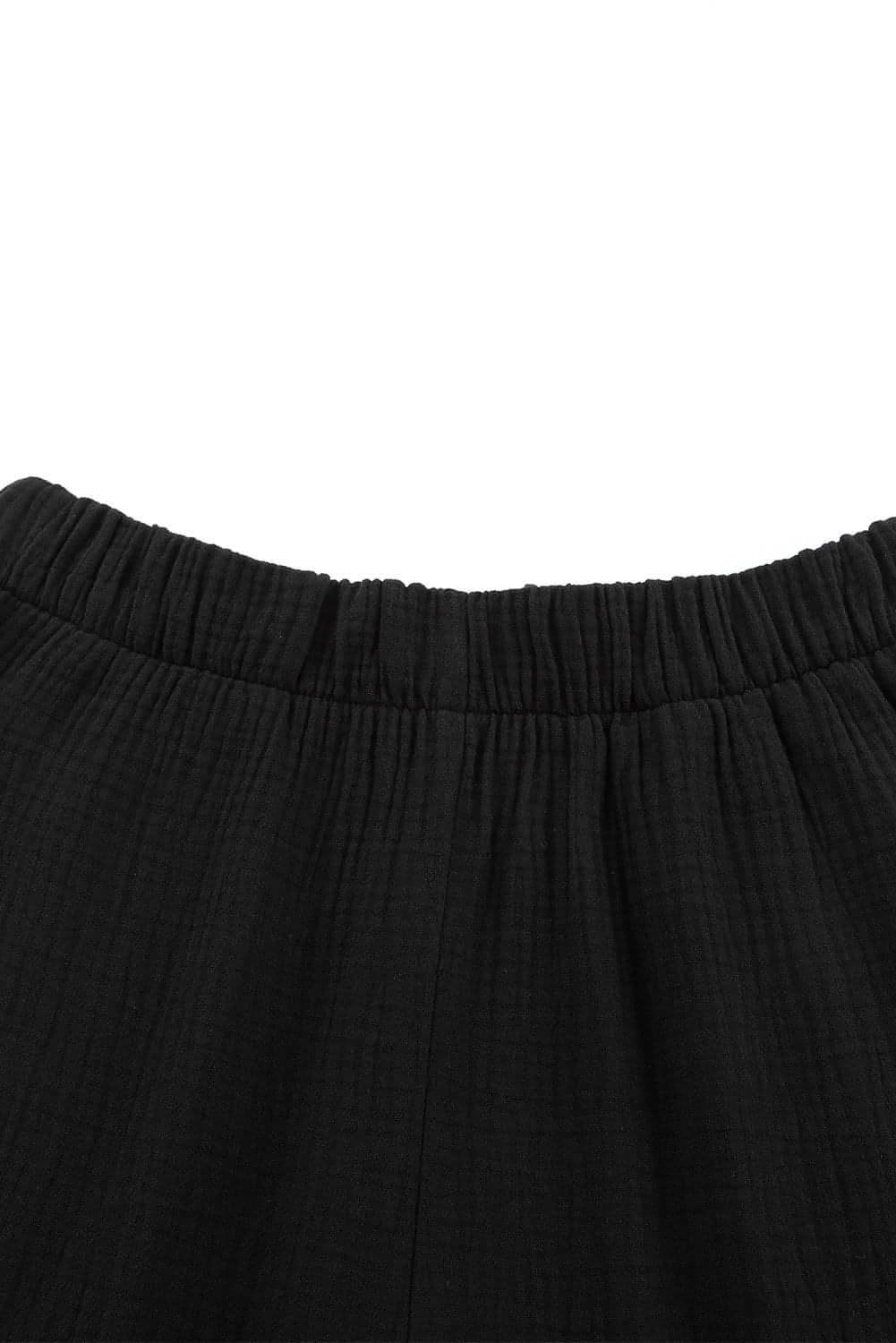 Black textured high waist ruffled bell bottom pants by Carmine Juneberry, featuring a stylish and flowy design.