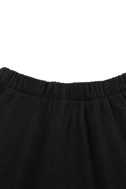 Black textured high waist ruffled bell bottom pants by Carmine Juneberry, featuring a stylish and flowy design.