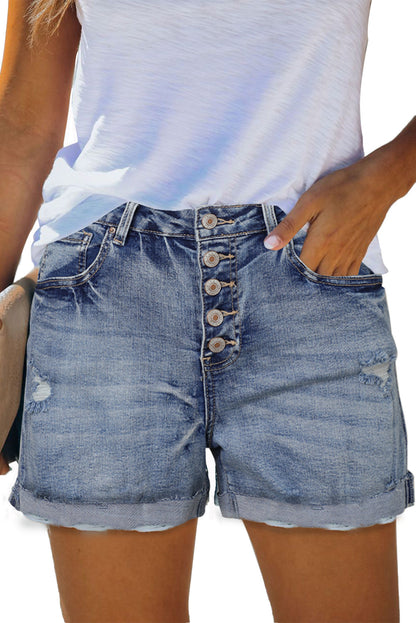 Distressed high rise button fly denim shorts by Harlequin Daisy, showcasing frayed edges and classic denim texture.