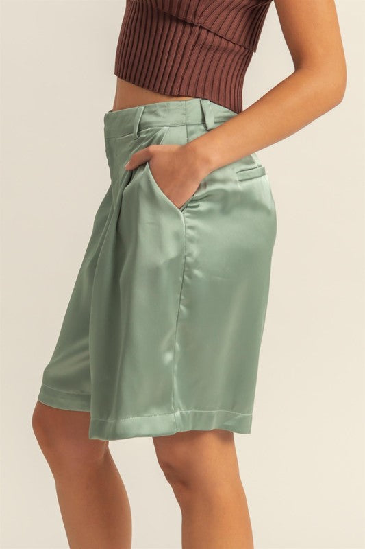 Satin high-waist pleated shorts by Jade Icarus, styled with a sleek automotive-inspired design, shown in a close-up image.