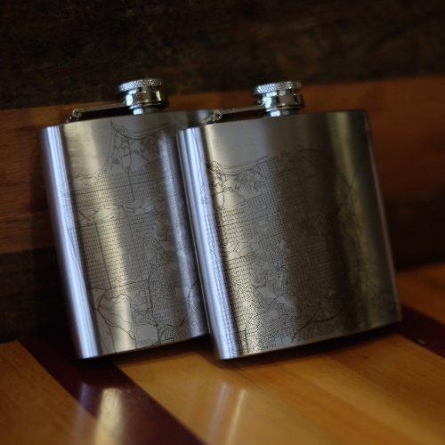 Cyan Castor Boyne Mountain Resort Michigan engraved topographic map hip flask on a wooden surface.