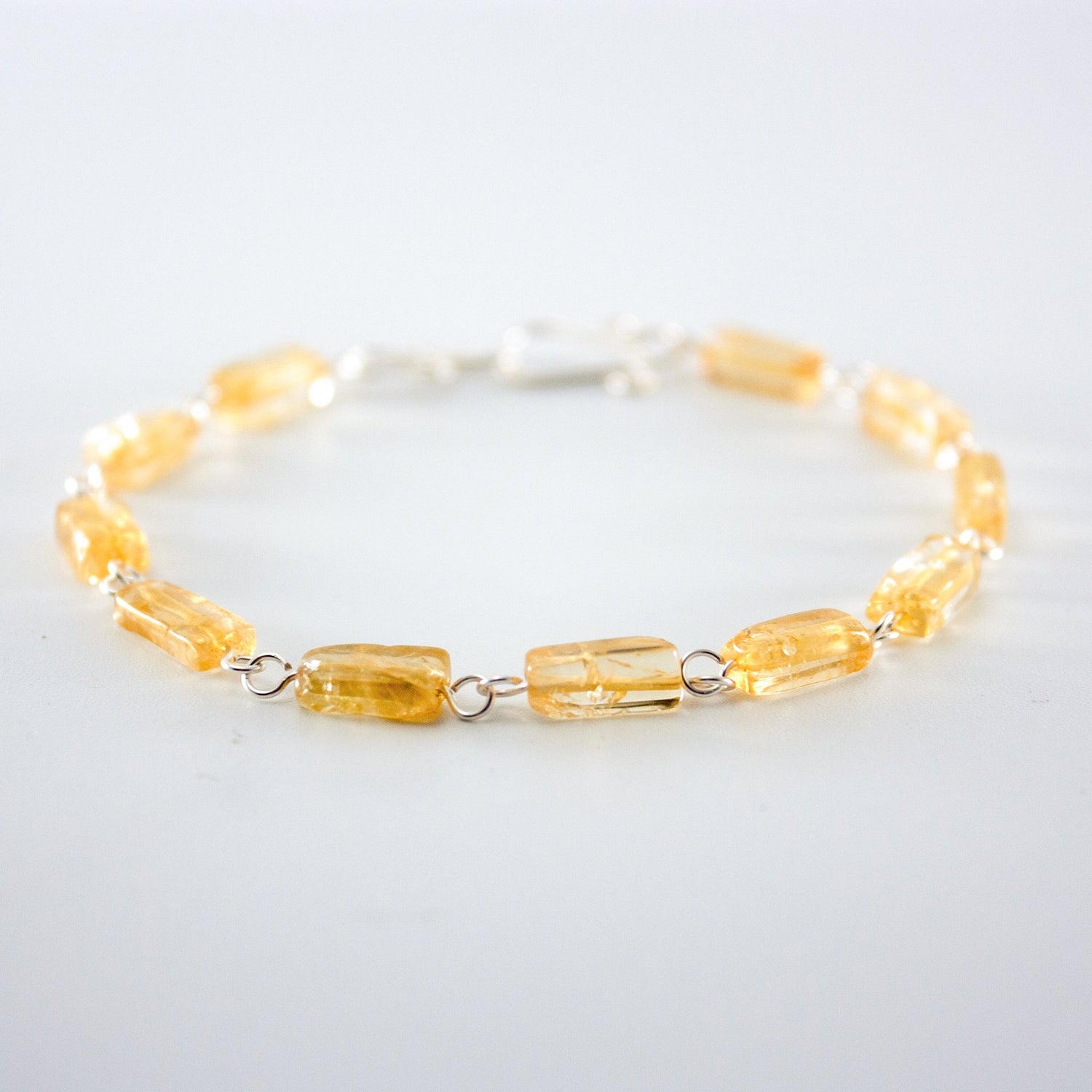 Silver rectangular citrine link bracelet by Grey Clymene featuring yellow gemstone accents and intricate silver chain links.