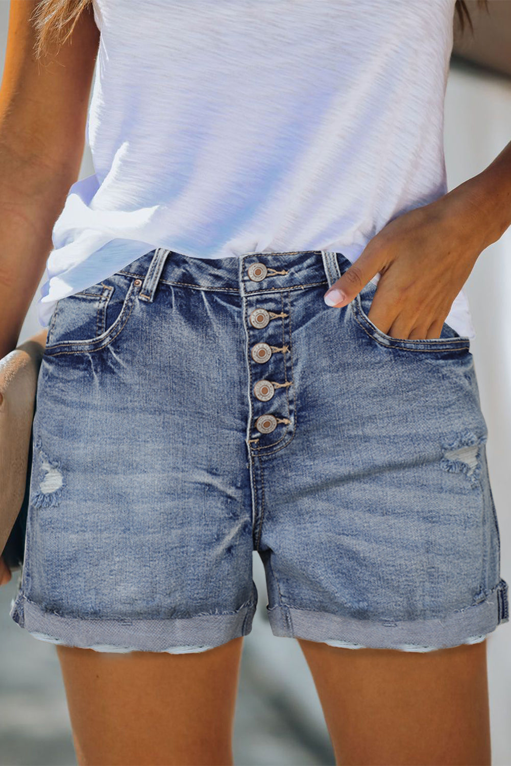 Distressed high rise denim shorts with button fly from Harlequin Daisy, showcasing casual style and frayed hem details.