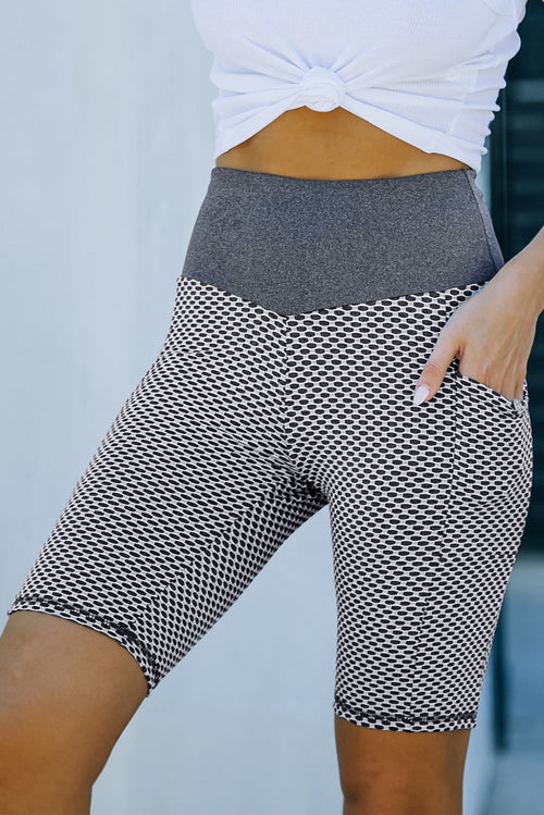 Black ruched yoga shorts with side pockets and butt lifting design by Harlequin Daisy, shown on a model in a fitness setting