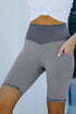 Black ruched yoga shorts with side pockets and butt lifting design by Harlequin Daisy, shown on a model in a fitness setting