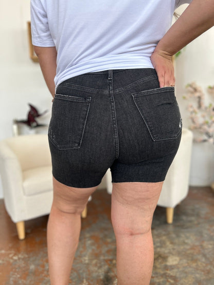 Judy Blue high waist rigid denim shorts for women with a classic fit, featuring a button and zipper closure and distressed details.