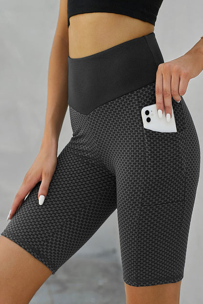 Black ruched yoga shorts with side pockets and lifting design by Harlequin Daisy, shown on a model for Bath &amp; Beauty collection.