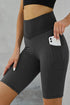 Black ruched yoga shorts with side pockets and butt lifting design by Harlequin Daisy, perfect for active wear and comfortable movement.