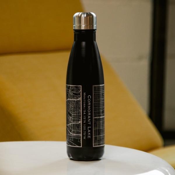 Cyan Castor Cormorant Lake Manitoba map insulated bottle in matte black, featuring a sleek design and lifestyle scene.