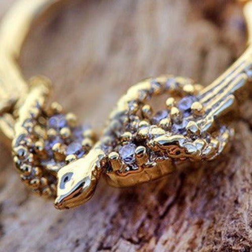 Gold plated jeweled wings and snake design septum ring from Peridot, showcasing intricate jewelry craftsmanship.