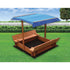 Kids wooden toy sandpit with canopy by Magenta Danae, featuring a wooden structure and colorful sand for outdoor play.