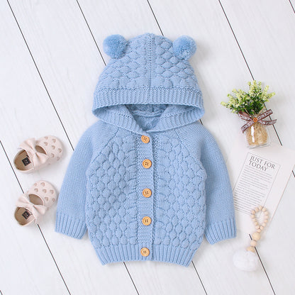 Baby wearing Carmine Juneberry KuschelGlöckchen™ hooded knit jacket with pom-pom, cozy baby clothing with a hood and decorative pom-pom.
