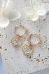 Ultramarine Birch 24 Karats Heart Hoop Earrings in gold, featuring a heart-shaped design and shiny finish, close-up view.