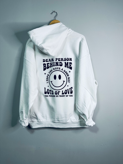 White hoodie from Emerald Ourea with "Dear Person Behind Me" text, casual sweater with a relaxed fit and drawstring hood.