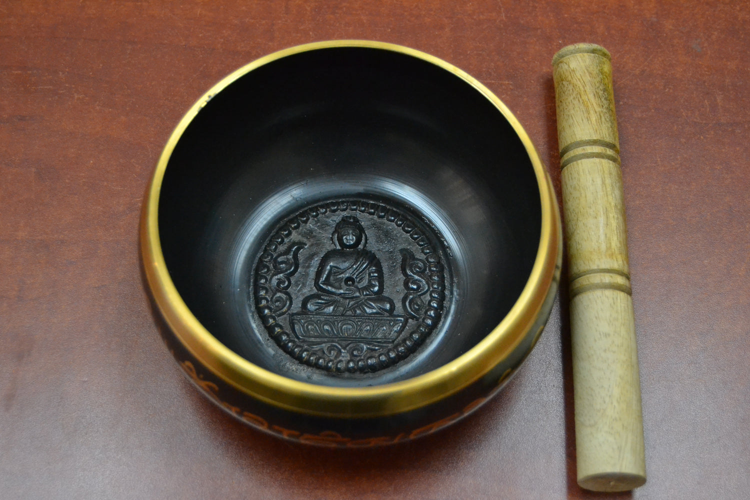 Handmade Nepal Tibetan brass singing bowl from Grey Aphrodite, shown with intricate carvings and a wooden striker on a neutral background.