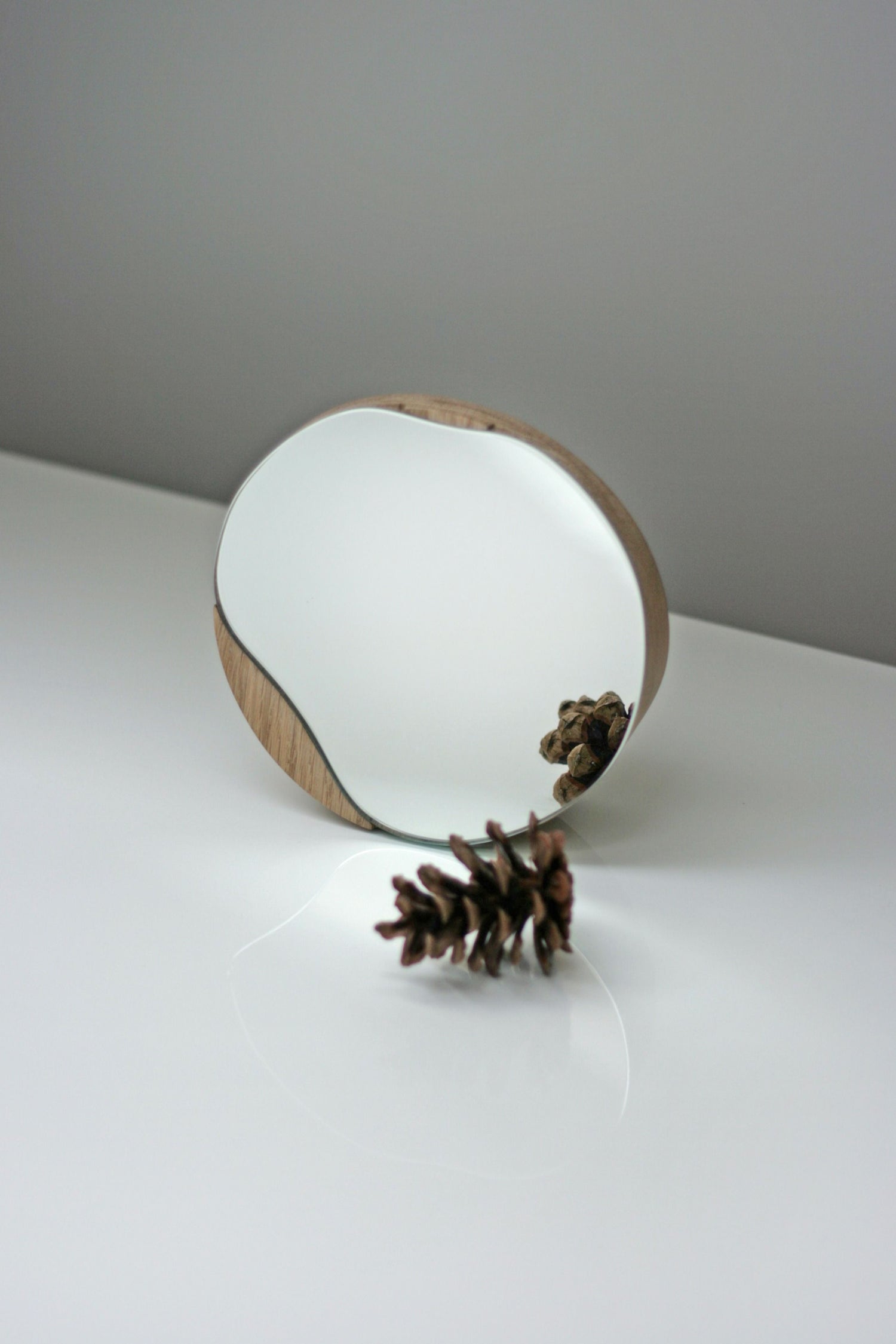 Biotite bathroom cosmetic round mirror with oak wood or black frame, designed for elegant bathroom decor.