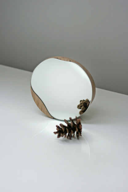 Biotite bathroom cosmetic round mirror with oak wood or black frame, designed for elegant bathroom decor.