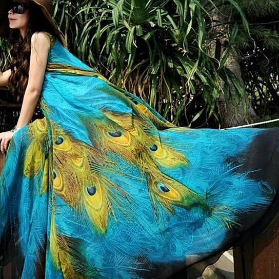 Yellow Pandora sleeveless peacock-themed long dress with intricate feather patterns and flowing fabric.