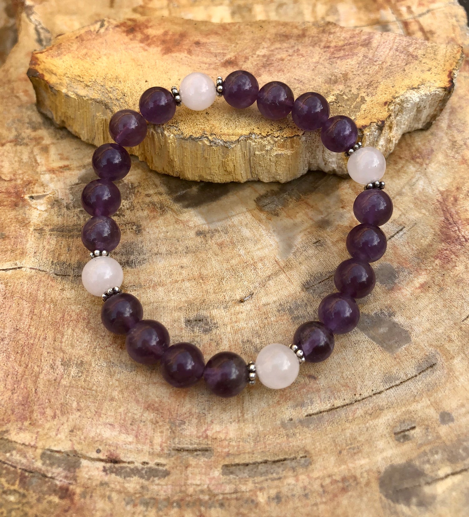 Amethyst and rose quartz stretch bracelet with natural crystals, featuring violet Chaos brand jewelry, on a neutral background.
