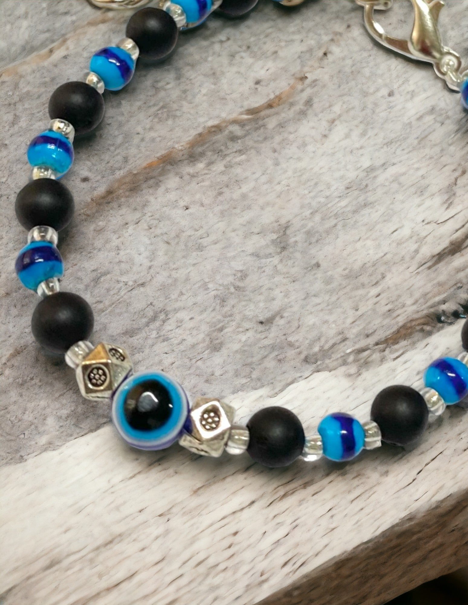 Gray Poseidon Fortune’s Shield Evil Eye bracelet featuring blue and silver beads on a stretch cord, designed for jewelry and protection.