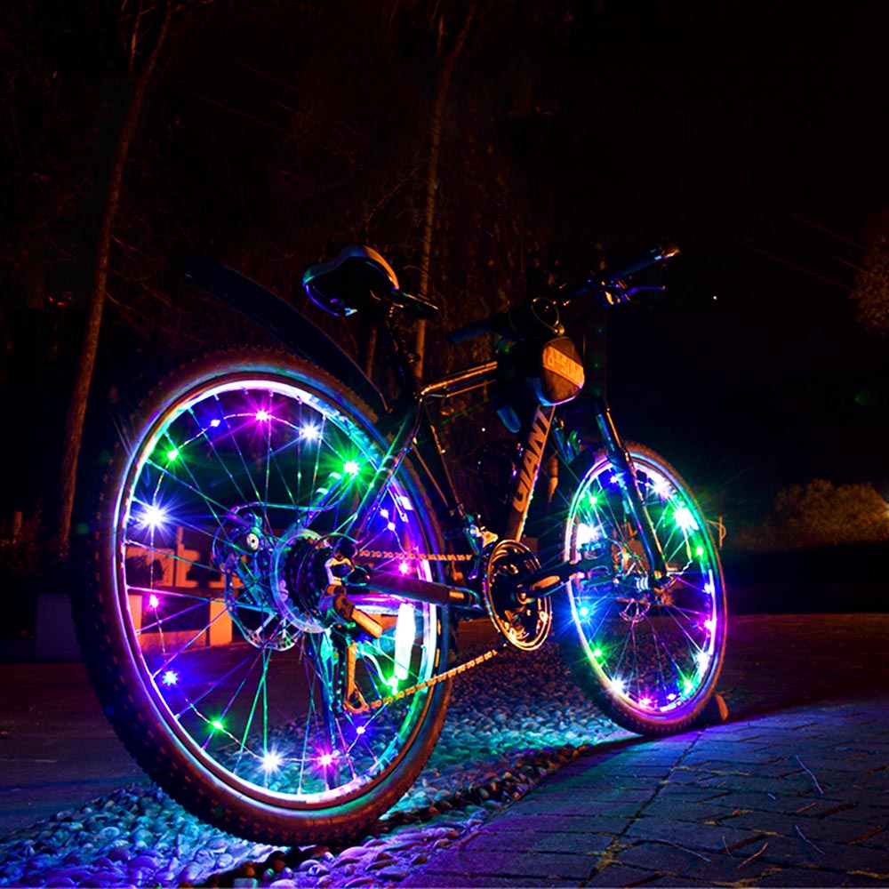 Colorful mini LED bike wheel spoke light by Lilac Milo, mounted on a bicycle wheel, creating vibrant illumination during biking.