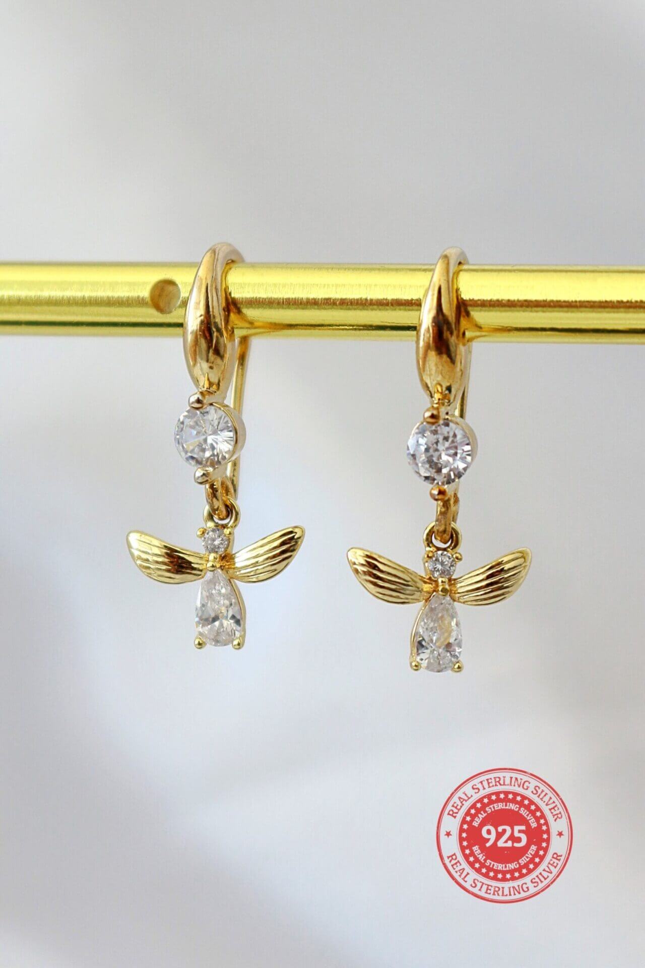 18 karat gold bee hook earrings by Ultramarine Birch featuring delicate bee-shaped dangle design with intricate detailing.