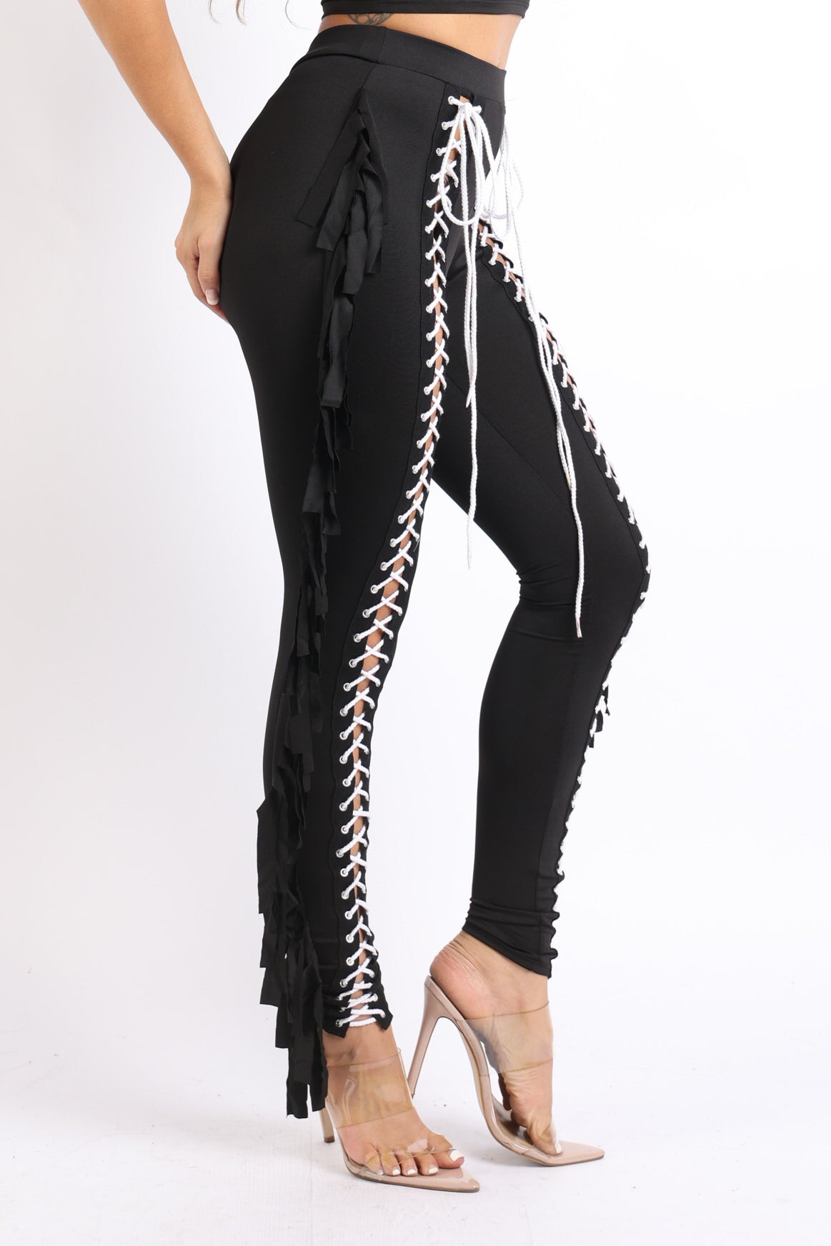 Black lace-up fringe tassel pants leggings by Puce Juniper with detailed fringe and tassel accents, shown on a model.
