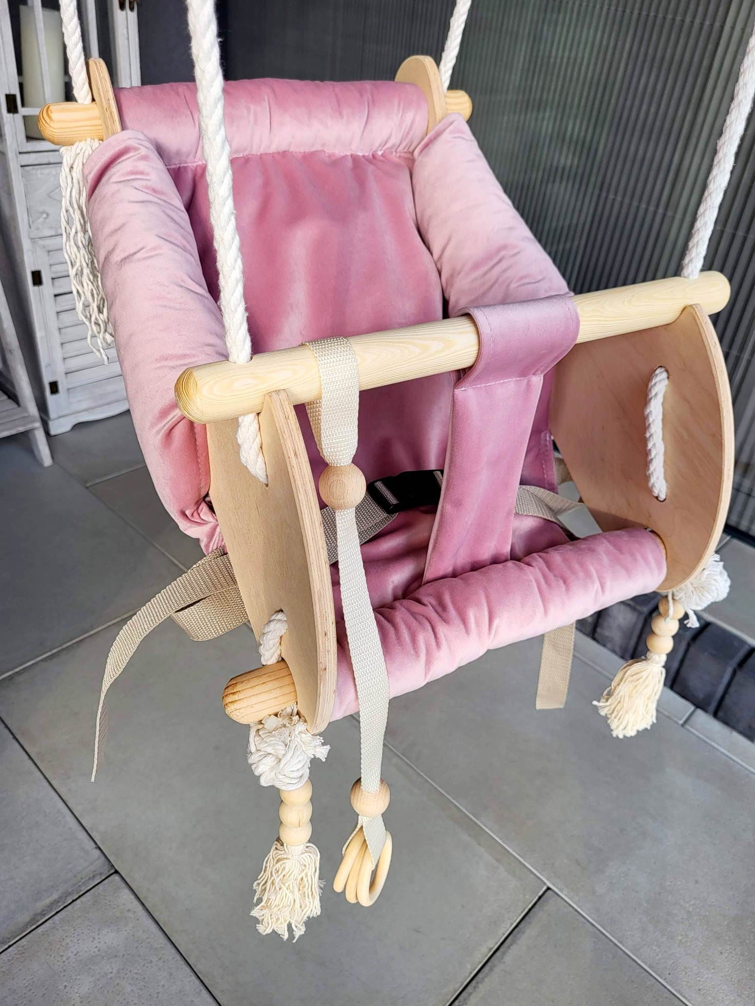 Pink Ochre Ares cradle-swing for kids and babies, showcasing a cozy, cushioned seat with safety harness and swinging mechanism.