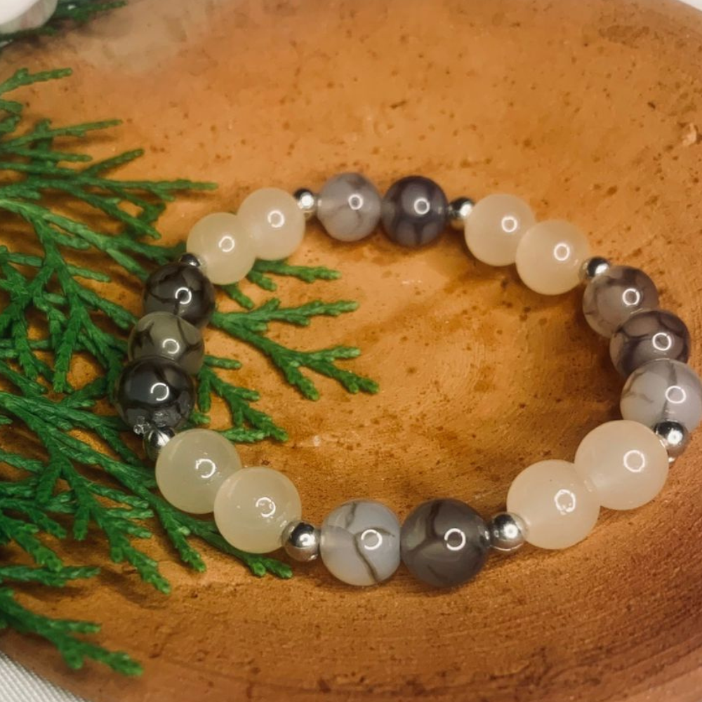 Gray and white agate gemstone beaded bracelet with silver spacers, featuring Tan Saffron branding on the jewelry.