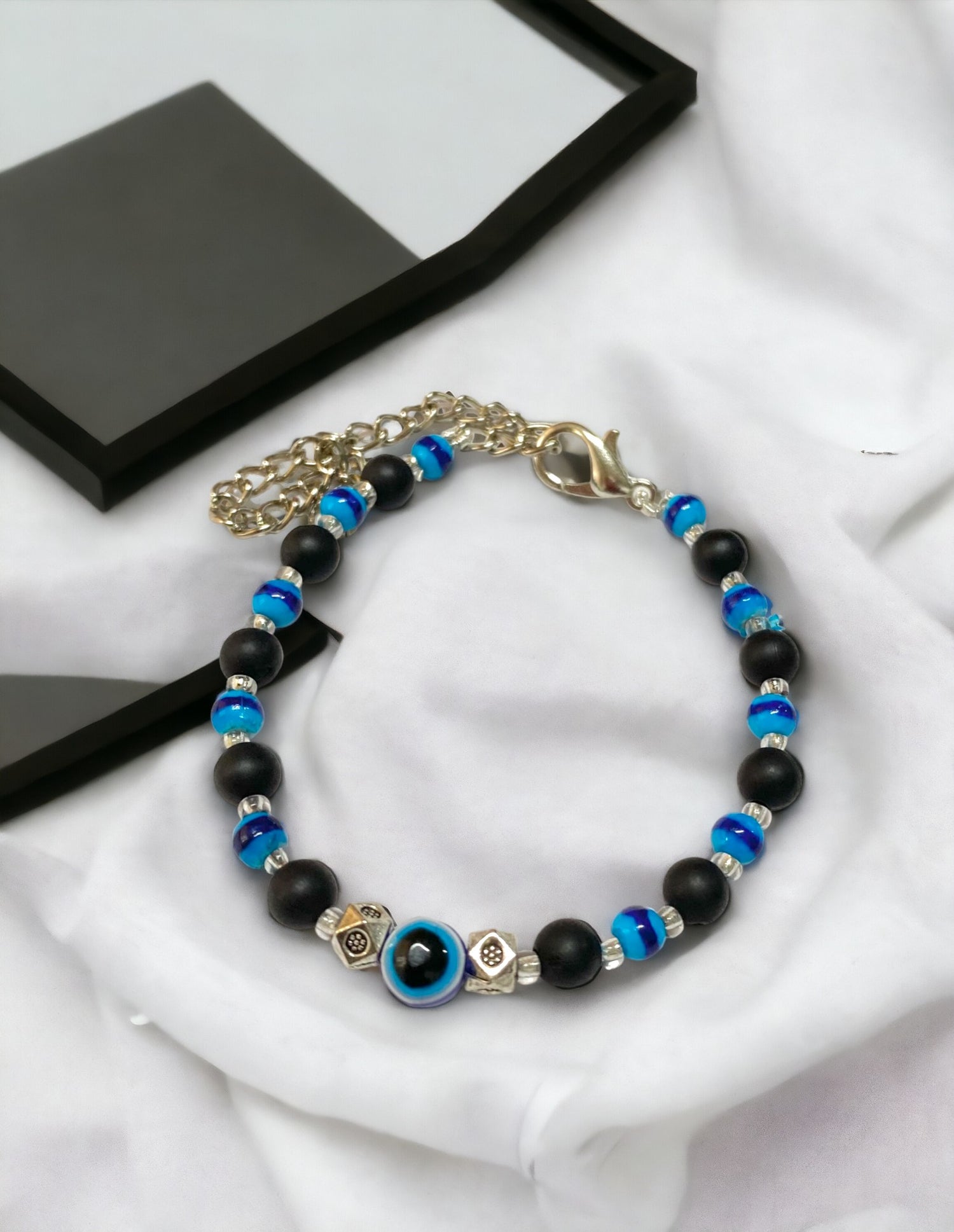 Gray Poseidon Fortune’s Shield Evil Eye bracelet featuring a silver-tone charm and vibrant blue evil eye bead on jewelry cord.
