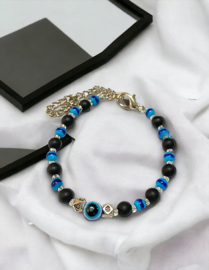 Gray Poseidon Fortune’s Shield Evil Eye bracelet featuring a silver-tone charm and vibrant blue evil eye bead on jewelry cord.