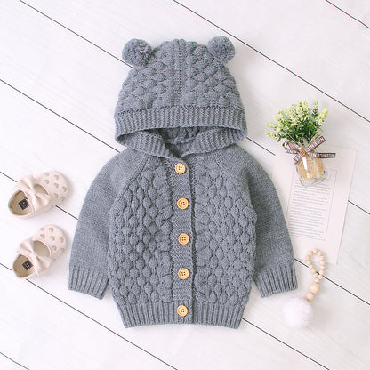 Baby wearing Carmine Juneberry KuschelGlöckchen™ hooded knit jacket with pom-pom, cozy baby clothing with adorable hood and pom-pom details.