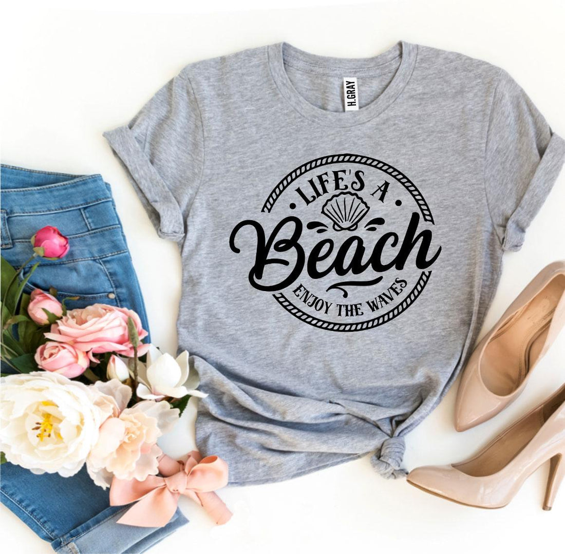 Agate Life’s a Beach Enjoy The Waves T-shirt showing a beach scene with waves and sun illustration on soft fabric.