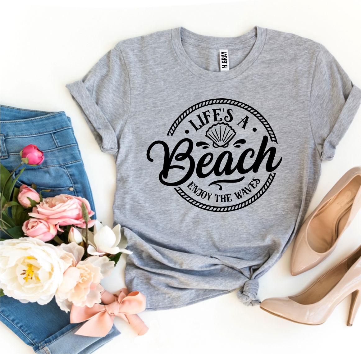 Agate Life’s a Beach Enjoy The Waves T-shirt showing a beach scene with waves and sun illustration on soft fabric.
