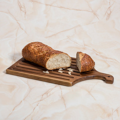 Azure Lily acacia wood slotted bread board, 10x18 inches, ideal for slicing and serving bread in a stylish kitchen setting.