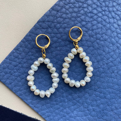 Yellow Athena pearl drop earrings featuring elegant white pearls hanging from delicate gold hooks.